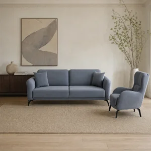 Puma Sofagarnitur in Blaugrau: Dreisitzer und Ohrensessel unter Stuckleisten, daneben dunkles Sideboard und Wandbild