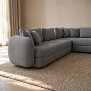 Nahaufnahme des linken Schenkels: gerundete Armrolle, bauchige Sitzkante und zurückgesetzter dunkler Sockel
