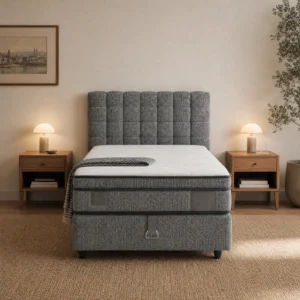 Frontansicht: graues Bett mit gerastertem Kopfteil, Bettkasten mit einer Zugschlaufe und Metallschnalle